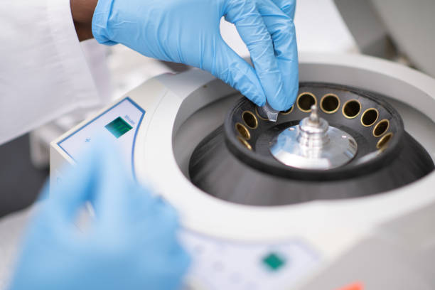 Samples Being Placed in a Centrifuge stock photo A Multi-ethnic woman wearing her protective medical gloves, places vials of medical samples, into the centrifuge to be spun to separate the differing densities of the sample. human centrifuge stock pictures, royalty-free photos & images