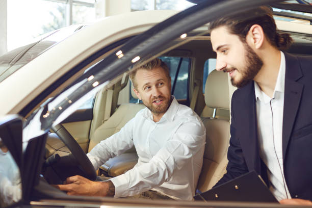 istock Auto dealer shows a new car to a man 1184005754