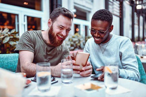 Swedish Male Laughing While Browsing Social Media With His African Friend
