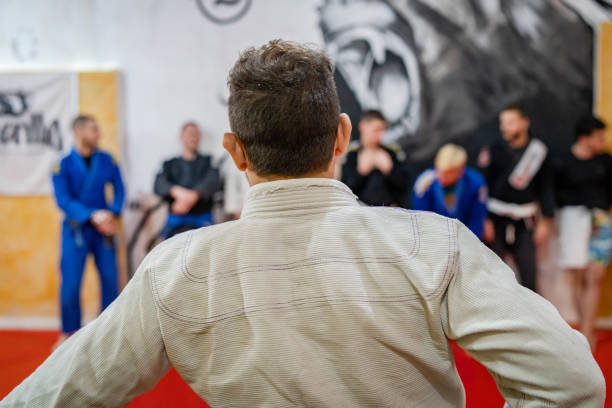 brasilianische jiu jitsu ausbildung bjj lehrer vor der linie seiner studenten an der akademie bei der trainingsklasse zurück ansicht - ju jitsu stock-fotos und bilder