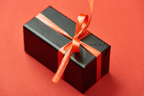 istock black gift box with bow and ribbon on red background 1184007884