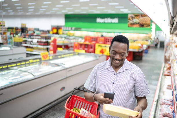 istock Mature man choosing product and using mobile phone in supermarket 1184008049