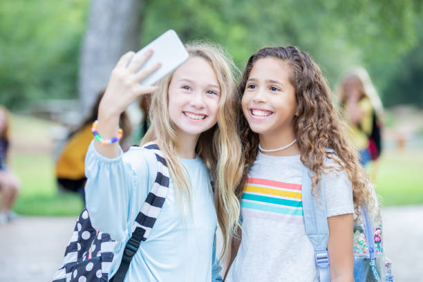 chicas preadolescentes tomando selfies juntos - schoolgirl pre adolescent child school children book bag fotografías e imágenes de stock