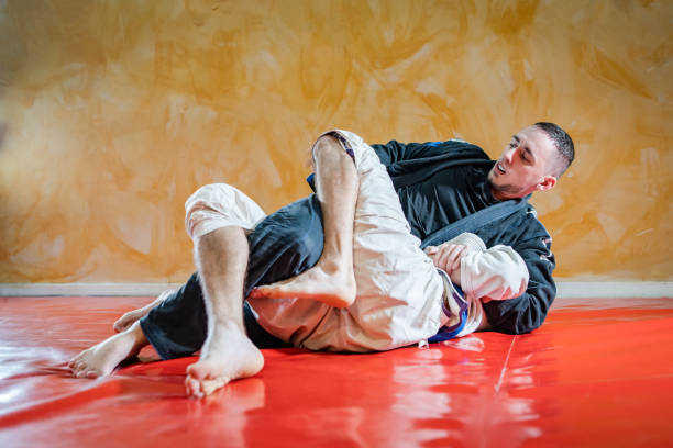 istock Two brazilian jiu jitsu athletes working on BJJ guard position at the training sparring or drilling fighters at the academy class 1184008900