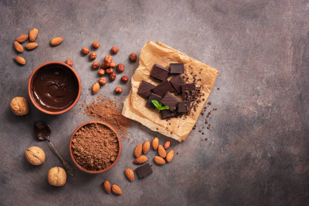 istock Melted chocolate, cocoa powder, chocolate slices, nuts and mint on a dark rustic background. Top view, flat lay, copy space. 1184009005