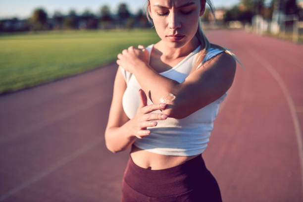 istock Female Putting Ointment On Injured Elbow Before Training 1184010483