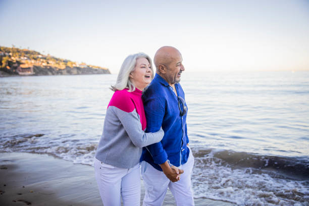 istock Senior Mixed Couple Walking along the Beach 1184012136