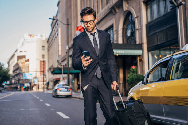 istock Man with mobile phone and suitcase outdoors 1184012640