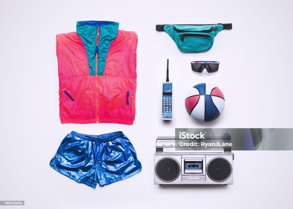 Nineties Basketball Fashion and Accessory Flat Lay Fluorescent windbreaker style clothing from the 1990's, along with accessories: fanny pack, brick phone, boombox, sunglasses, and basketball.  Knolling layout. Waist Pack Stock Photo