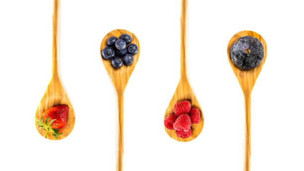 five wooden spoons with fruits on it stock photo