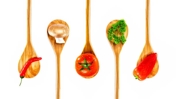 five wooden spoones with vegetables on it stock photo