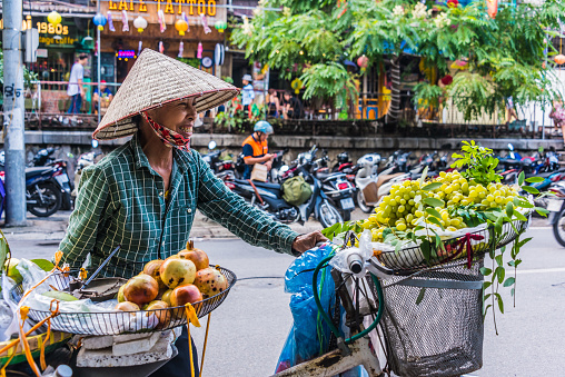 HANOI, VIETNAM - SEP 19, 2019: Vietnamese woman selling fruit on a bike in the old town of Hanoi, Vietnam