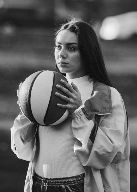 Nineties Basketball Fashion and Accessory Woman A young woman plays on a basketball court wearing a fluorescent windbreaker style, from the 1990's, along with accessories: fanny pack, brick phone, boombox, sunglasses, and basketball. 1980 photos stock pictures, royalty-free photos & images