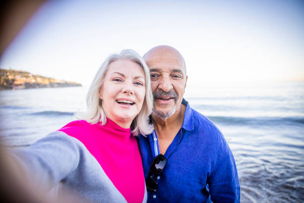 istock Senior Mixed Couple Walking along the Beach 1184013965