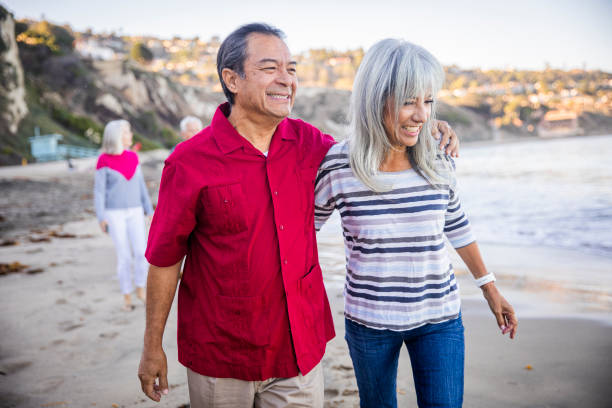 couples hispaniques aînés marchant le long de la plage - palos verdes photos et images de collection