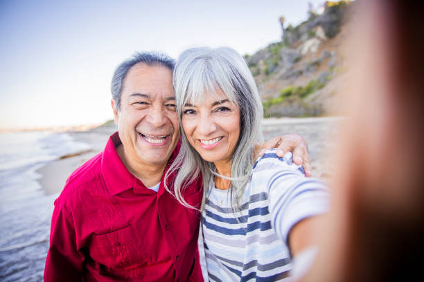 istock Senior Hispanic Couple Taking Selfie at the Beach 1184015102