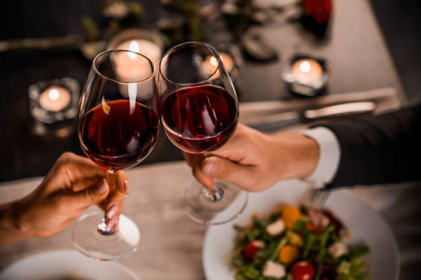fermez-vous vers le haut de jeunes couples griller avec des glaces de vin rouge au restaurant - saint valentin photos et images de collection