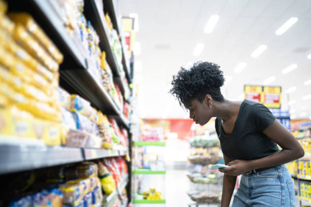 istock Young woman using mobile phone in supermarket 1184016851