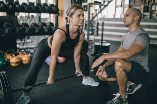 istock Woman exercise with barbell with her personal trainer 1184017810