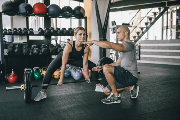istock Woman exercise with barbell with her personal trainer 1184017867