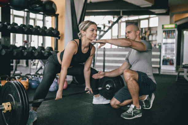 istock Woman exercise with barbell with her personal trainer 1184017919