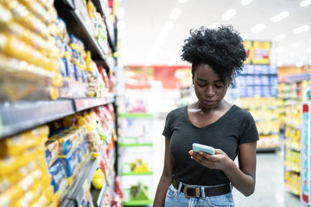 istock Young woman using mobile phone in supermarket 1184017956