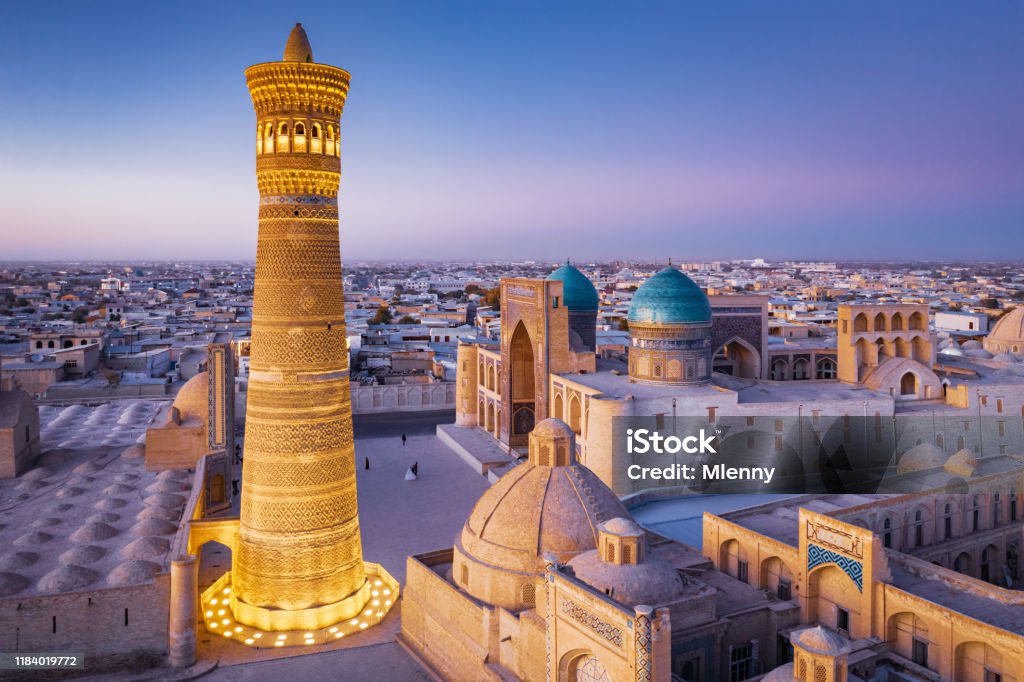 Bukhara Uzbekistan Kalyan Minaret and Madressa Sunset Twilight Colorful sunset twilight over the famous Old Town in the City of Bukhara with the iconic Kalyan Minaret and Miri Arab Madressa. Aerial Drone Point of View. Itchan Kala, Bukhara, Khorezm Region, Uzbekistan, Central Asia. Uzbekistan Stock Photo