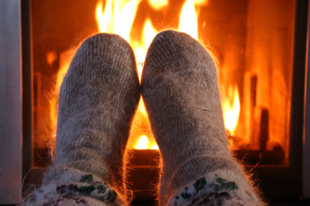 istock Feet in wool socks warming at the fireplace 1184025532