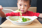 アジアの3 - 4歳の幼児の男の子は、自宅で昼食のためにスプーンでチーズと焼かれたほうれん草を食べる、小さな子供の笑顔と食べ物を見て