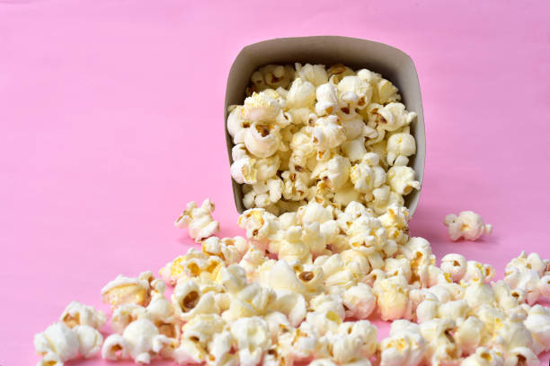 istock popcorn falling from paper packaging with pink background. 1184034923