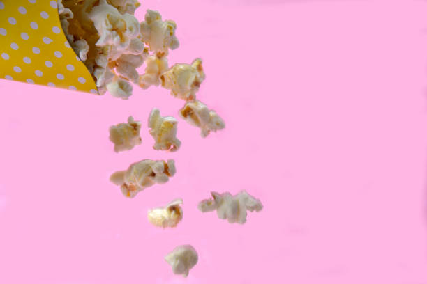 istock popcorn falling from paper packaging with pink background. 1184035024