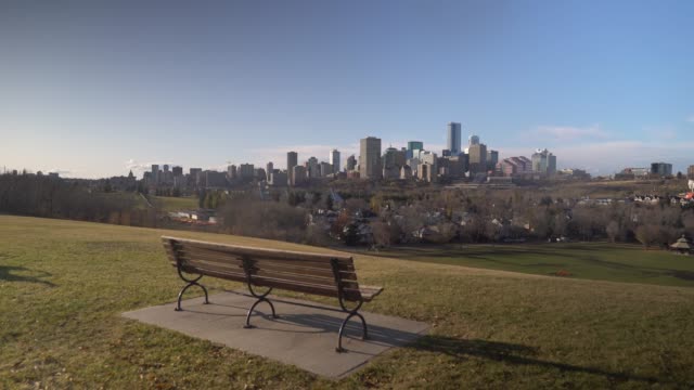 Establishing shot of Edmonton skyline with a bench in the foreground