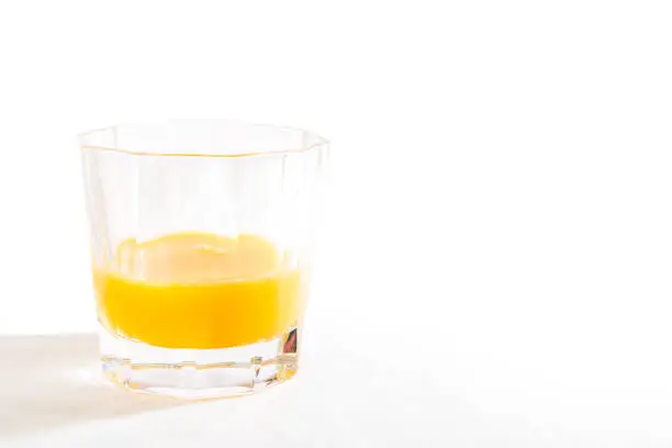 Photo of A glass tumbler filled with orange juice isolated on a white background