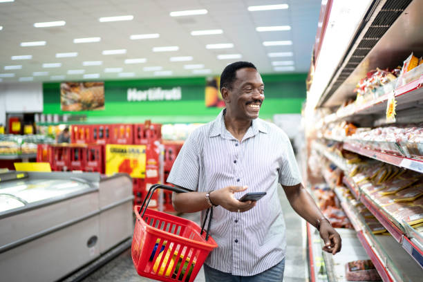 Mature man choosing products in supermarket Mature man choosing products in supermarket holding shopping basket stock pictures, royalty-free photos & images