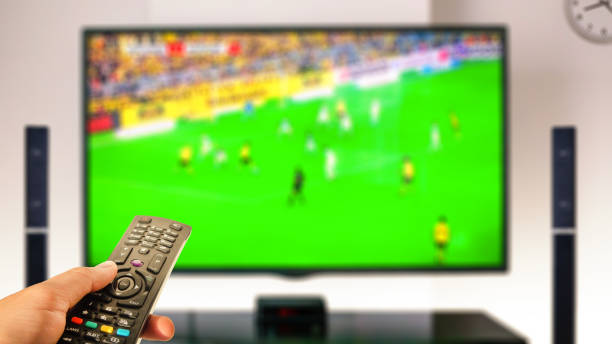 watching soccer at home tv with remote control on hand watching soccer at home tv with remote control on hand tv game stock pictures, royalty-free photos & images