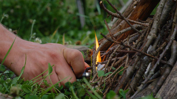 istock MACRO, DOF: Man's hand holds a lighter and ignites a campfire in the wilderness. 1184048541