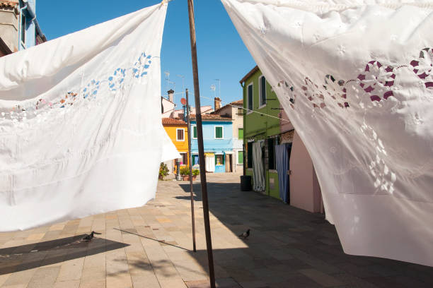 Colourful houses walls with hanging lace sheets in Burano, Venice, Italy Burano lace is one of the most famous lace in the world, with a centuries-old and specific tradition on the island of Burano, in the Venice lagoon. lacemaking photos stock pictures, royalty-free photos & images