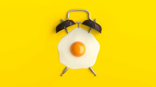 istock Alarm clock with a fried egg shape on yellow color. 1184059207