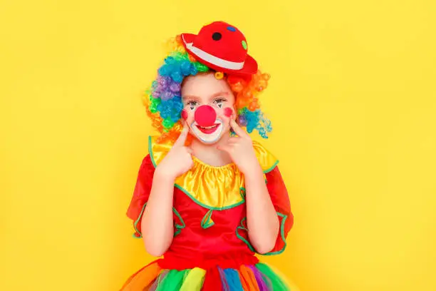 Photo of Portrait of cute girl clown , toothy smiling, looking at camera