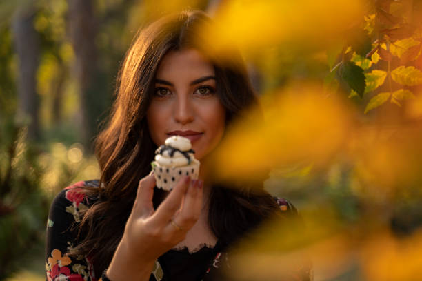 istock Gorgeous girl holding cupcake in park 1184068852