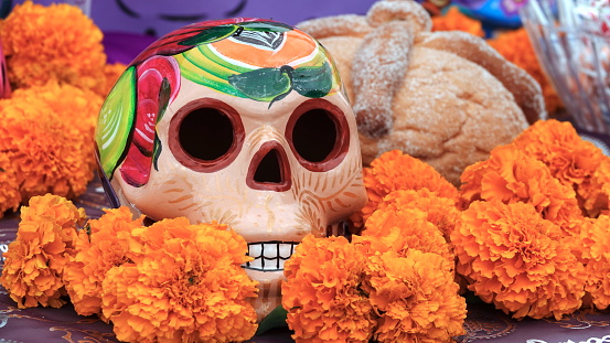Sugar skull, sweet bread called pan the muerto and marigold flowers at Day of the Dead (Dia de los Muertos) altar.