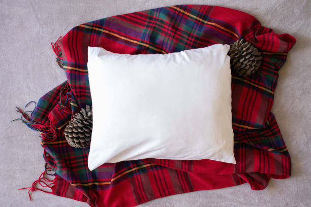 istock Blank white rectangle cushion laying on a tartan Christmas scarf with a light grey background - Christmas autumn pillow mockup 1184073180