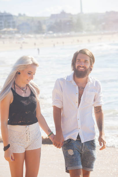 Young couple spending time together at the beach walking holding hands.