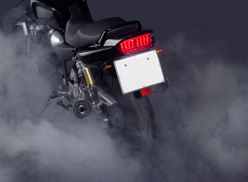 detail of a motorbike and lots of smoke in dark back