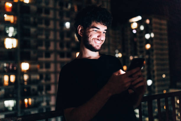 istock Young man using smartphone on residential balcony at night 1184082198