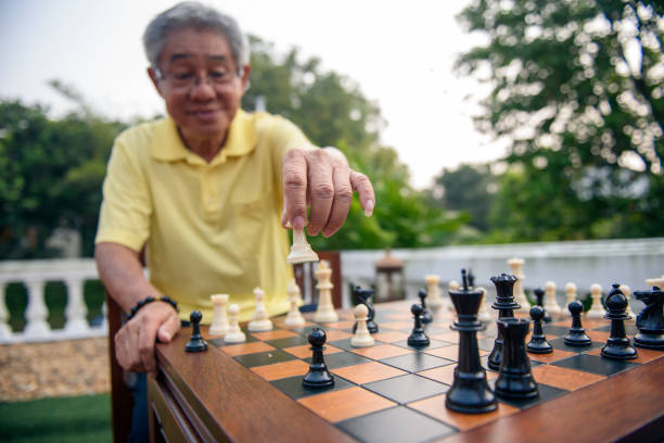 Grandfather Playing Chess Board Game At Garden