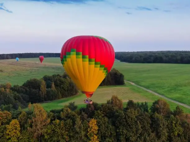 Aerial view of air balloons flights from altitude in summer above the river. Drone panorama. Beautiful landscape scene.