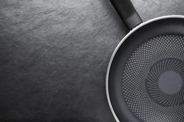 Black skillet with non-stick coated surface on dark slate background