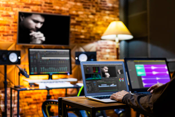 professional director, editor, producer editing movie footage and music score track on computer in digital editing, post production, broadcasting studio stock photo