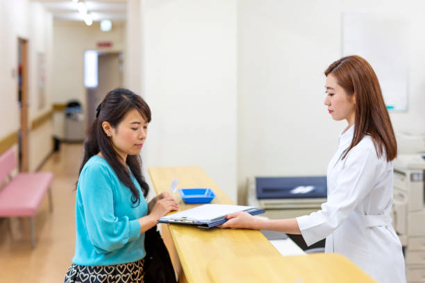 istock Mother Filling in Paperwork at a Hospital Reception 1184102949